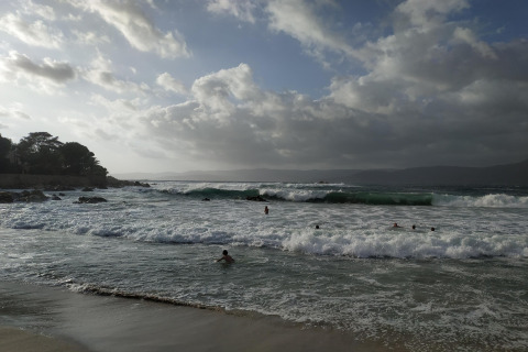Imagen de olas y nadadores en la playa frente a Résidence U Livanti Belvédère Campomoro en Francia.