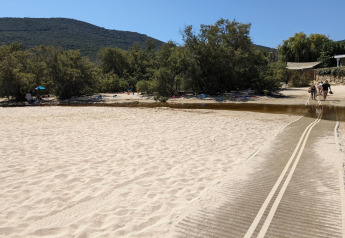 Zandstrand met loopmat en bomen bij Résidence U Livanti Belvédère Campomoro in Frankrijk.