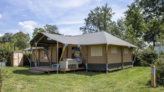 Safari Villa safaritelten på ferieparken De Boshoek i Holland, beliggende på grøn græsplæne omgivet af træer.