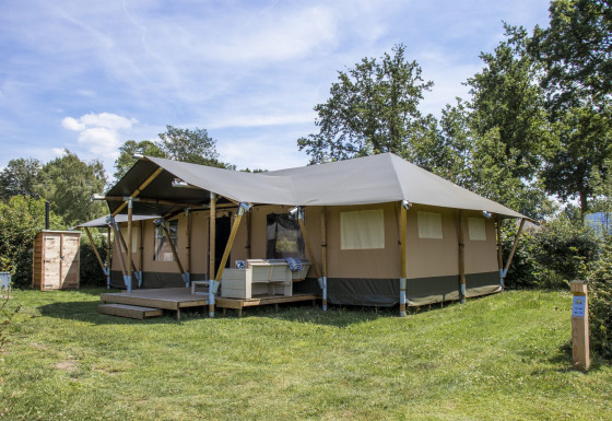 Safari Villa safaritelten på ferieparken De Boshoek i Holland, beliggende på grøn græsplæne omgivet af træer.