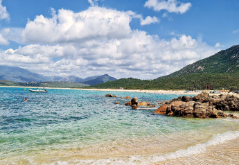 Herrlicher Strandblick mit klarem Wasser, Felsen und Bergen bei Résidence U Livanti Belvédère Campomoro, Frankreich.