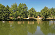 Blick auf die Cottage «6p» Mobilheime in Frankreich, von Bäumen gesäumt am Ufer eines Sees.