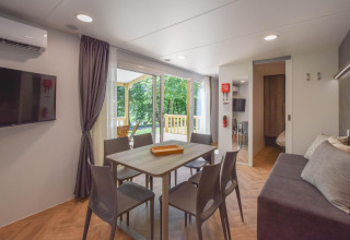 Sala moderna en una mobil home Cottage 6p en Francia, con mesa comedor, sofá y vistas a la terraza.