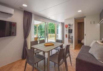Modernes Wohnzimmer im Mobilheim Cottage 6p in Frankreich mit Esstisch, Sofa und großer Terrasse.