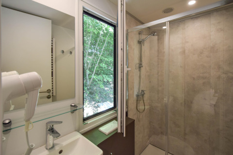 Badkamer in het mobilhome Cottage ‘6p’ in Frankrijk met douche, raam met boszicht en moderne faciliteiten.
