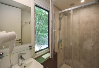 Baño en casa móvil Cottage «6p» en Francia con ducha, ventana con vistas a árboles y comodidades modernas.