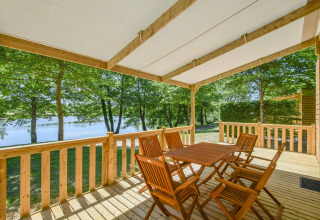 Træterrasse med bord og stole i mobilhjem Cottage 6p i Frankrig, udsigt over sø og grøn natur.