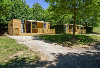 Casa móvil moderna Cottage «6p» en Francia, porche de madera, césped y árboles verdes rodeando el lugar.