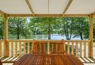 Zicht vanop het houten terras met tafel en stoelen op het meer bij Cottage 6p mobilhome in Frankrijk.