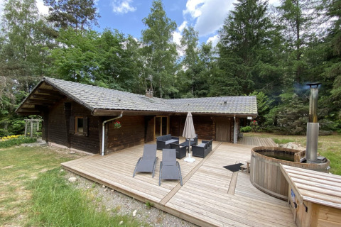 LE FISHING LODGE houten chalet met terras, tuinmeubilair en een nordisch bad in een bosrijke omgeving.
