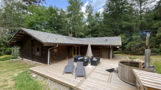 LE FISHING LODGE houten chalet met terras, tuinmeubilair en een nordisch bad in een bosrijke omgeving.