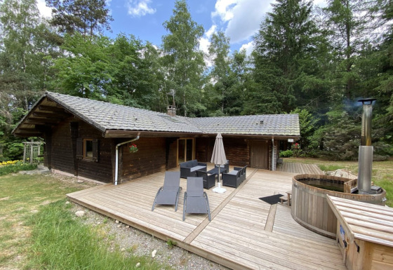 Chalet in legno LE FISHING LODGE con terrazza, salotto da esterno e bagno nordico tra gli alberi.