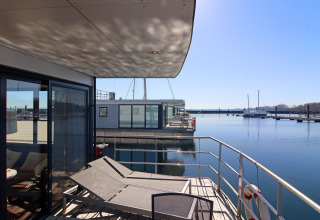 Modern houseboat terrace with sun loungers overlooking the marina at Houseboat «Familiy & Friends LP 1» in Germany.