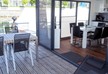 Comedor moderno y terraza de casa flotante con mesa, sillas y vista al agua en Alemania.