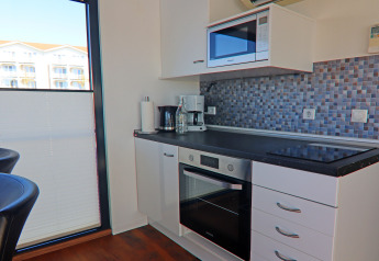 Cocina moderna de casa flotante con horno, microondas, cafetera y pared con azulejos de mosaico.