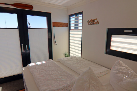 Bright bedroom on the 'Family & Friends LP 1' houseboat in Germany with large windows and cozy decor.