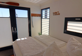 Bright bedroom on the 'Family & Friends LP 1' houseboat in Germany with large windows and cozy decor.