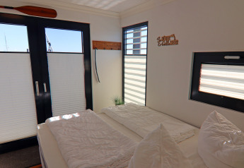 Camera luminosa sulla houseboat 'Family & Friends LP 1' in Germania, con grandi finestre e arredo semplice.