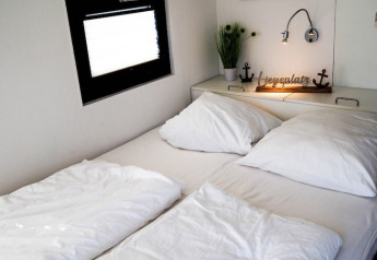 Camera da letto su una houseboat in Germania con letto matrimoniale, lenzuola bianche e decorazioni.