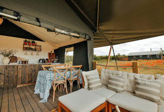 Interieur van safaritent Owls Nest in het Verenigd Koninkrijk, met keuken, eettafel en zithoek.