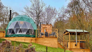 Ashdown Luxury Dome avec dôme géodésique, terrasse en bois, coin salon extérieur et fond boisé.