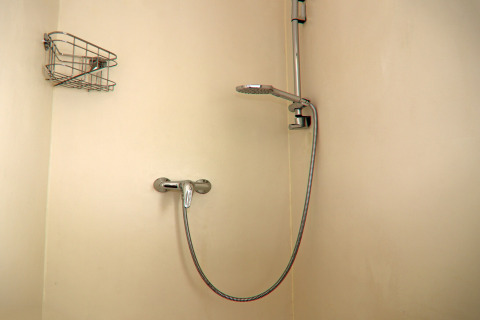 Modern shower setup on a houseboat, featuring a wall-mounted showerhead and metal shelf for toiletries.