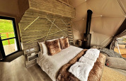 Interieur van de Wakehurst Luxury Dome in het VK met comfortabel bed, haard en moderne details.