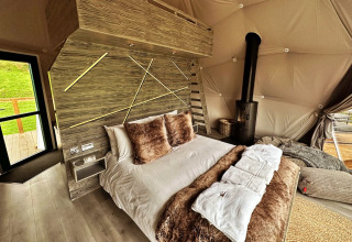 Interieur van de Wakehurst Luxury Dome in het Verenigd Koninkrijk met knus bed en moderne haard.