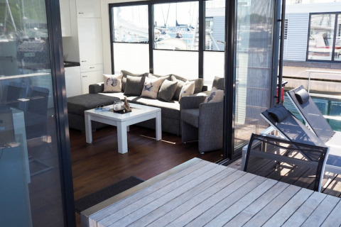 Living room with sofa, coffee table and large windows on houseboat “Familiy & Friends LP 1 / 4 Personen” in Germany.