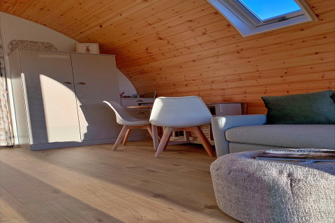 Modern houten pod-interieur met dakraam, sofa, stoelen en kast bij Hundle Dale, Verenigd Koninkrijk.