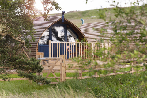 Knusse houten glamping-pod met omheind terras bij Blackcleugh Glamping, Verenigd Koninkrijk, omgeven door natuur.