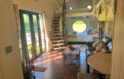 Interno della casa mobile Oak Tree Lodge nel Regno Unito con divano, scala a chiocciola e finestre rotonde.
