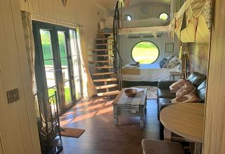 Intérieur du mobil-home Oak Tree Lodge au Royaume-Uni avec canapé, escalier en colimaçon et grandes fenêtres.