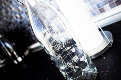 Clear glass bottle with the word 'water' and hearts, standing on a kitchen counter on a houseboat in Germany.