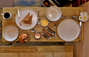 Kleiner Holztisch mit Toast, Butter, Kaffee und Gänseblümchen im 'Marared' Gypsy Hut, Großbritannien.