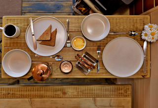 Tiny wooden breakfast table with toast, butter, coffee and flowers at 'Marared' Gypsy Hut, United Kingdom.