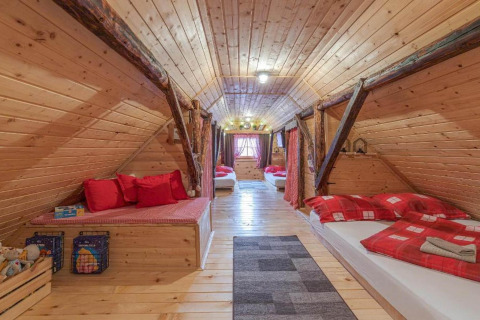 Knusse houten zolderkamer met rode bedden en gezellige uitstraling in Stara Hiža Vlašić, Kroatië.