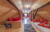 Cozy wooden loft bedroom with red bedding, sloped ceiling and rustic decor in Stara Hiža Vlašić, Croatia.