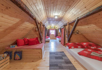 Accogliente camera mansardata in legno con letti rossi e atmosfera rustica presso Stara Hiža Vlašić, Croazia.
