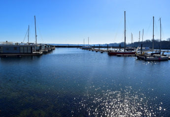 Zonnige dag aan de jachthaven met woonboot en zeilboten bij Houseboat Family & Friends in Duitsland.