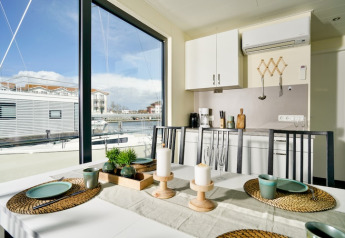 Comedor en la casa flotante Family & Friends LP 3 con vista al puerto y decoración moderna en Alemania.
