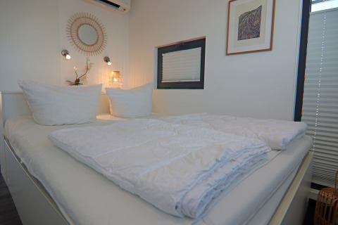 Modern bedroom on the Family & Friends LP 3 houseboat in Germany, featuring white bedding and cozy decor.