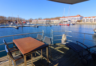 View from houseboat terrace with table and chairs overlooking marina, boats, and apartments in Germany.