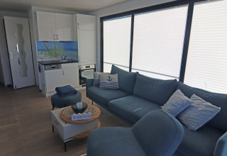Modern living room and kitchenette on Houseboat Family & Friends LP 4 with blue sofa and large windows.