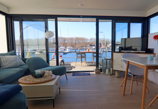 Luminoso salón en una casa flotante con vistas a la terraza y un puerto deportivo en Alemania.