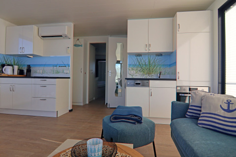 Modern houseboat interior with open kitchen, nautical-themed decor, and cozy seating area.