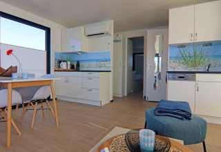 Moderne åbent køkken-alrum på husbåd med spisebord, stilige stole og maritimt dekoreret køkken i Tyskland.