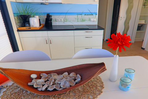 Modern houseboat kitchen with wooden decor, red flower in vase and blue tealights on the dining table.