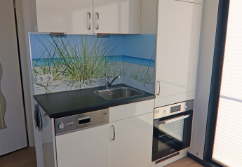 Petite kitchenette moderne sur une péniche en Allemagne, avec évier, four et décor de plage mural.