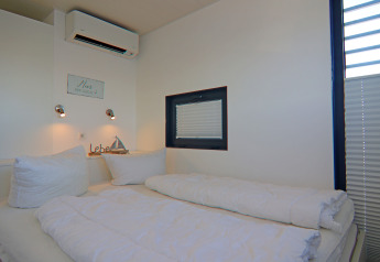 Chambre avec lit double, oreillers blancs, éclairage moderne et fenêtre sur une péniche en Allemagne.